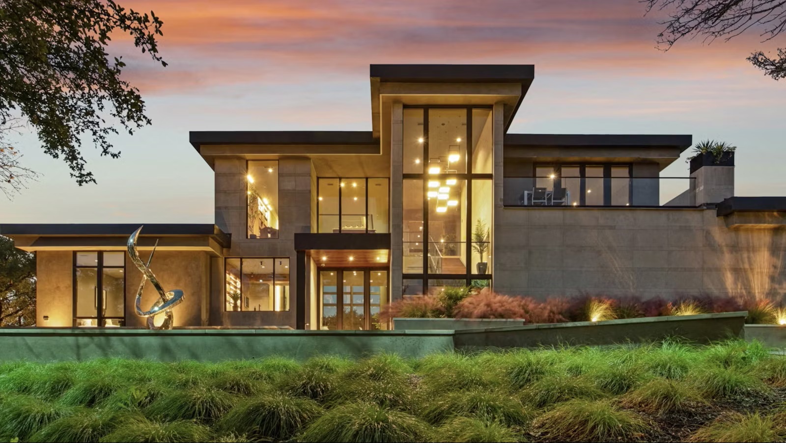 Modern luxury home with large glass windows glowing at dusk
